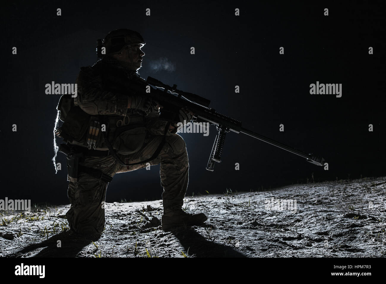 Army Sniper mit großen sitzen Holding Gewehr Gewehr Stockfoto