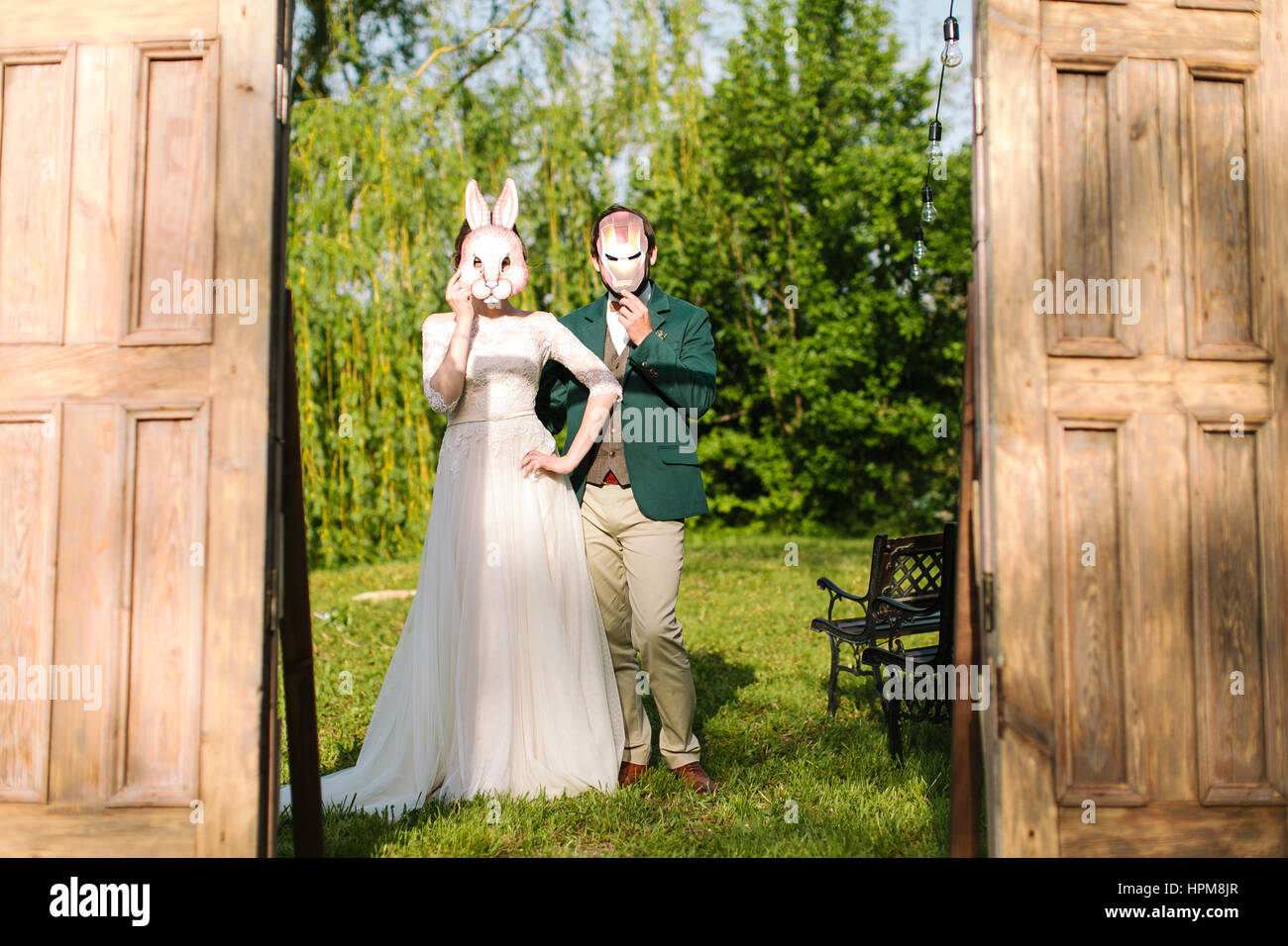 der Bräutigam und die Braut haben eine Maske mit lustigen Cartoon-Helden auf Gesichter zaubern. Das lustige Foto mit Brautpaar. Stockfoto