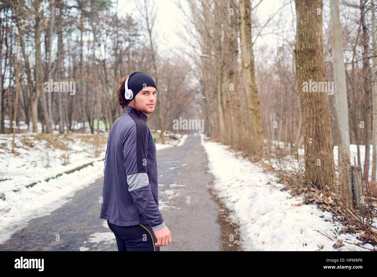 Sport-Guy in Kopfhörer und Hut im park Stockfoto