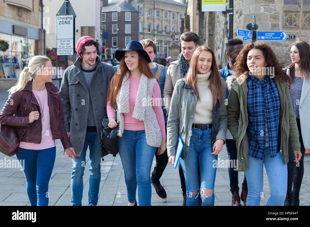 Eine glückliche Gruppe von Jugendlichen Studenten Lächeln, als sie ihren Weg zu ihren Klassen für Universität machen. Sie tragen ihre Taschen, Bücher und Technologie Witz Stockfoto
