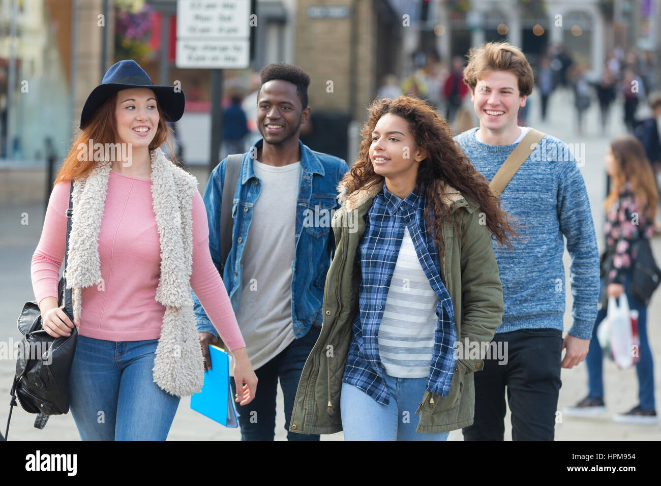 Eine glückliche Gruppe von Jugendlichen Studenten Lächeln, als sie ihren Weg zu ihren Klassen für Universität machen. Sie tragen ihre Taschen, Bücher und Technologie Witz Stockfoto