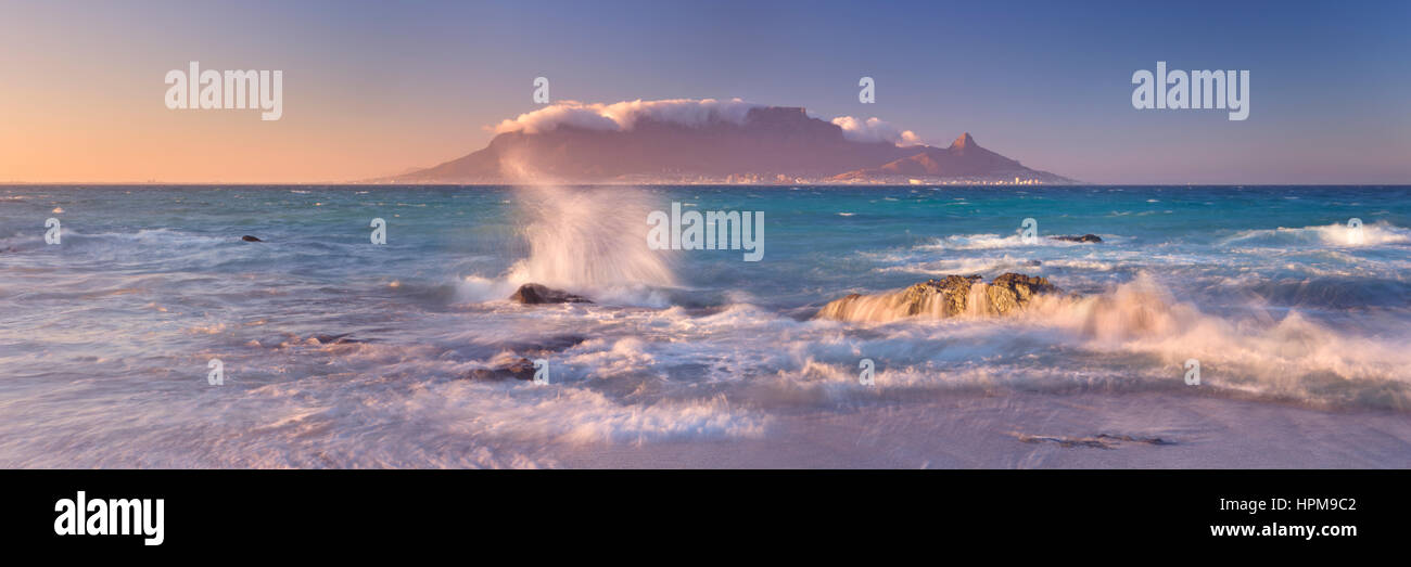 Sonnenaufgang über dem Tafelberg und Kapstadt vom Strand Bloubergstrand. Stockfoto