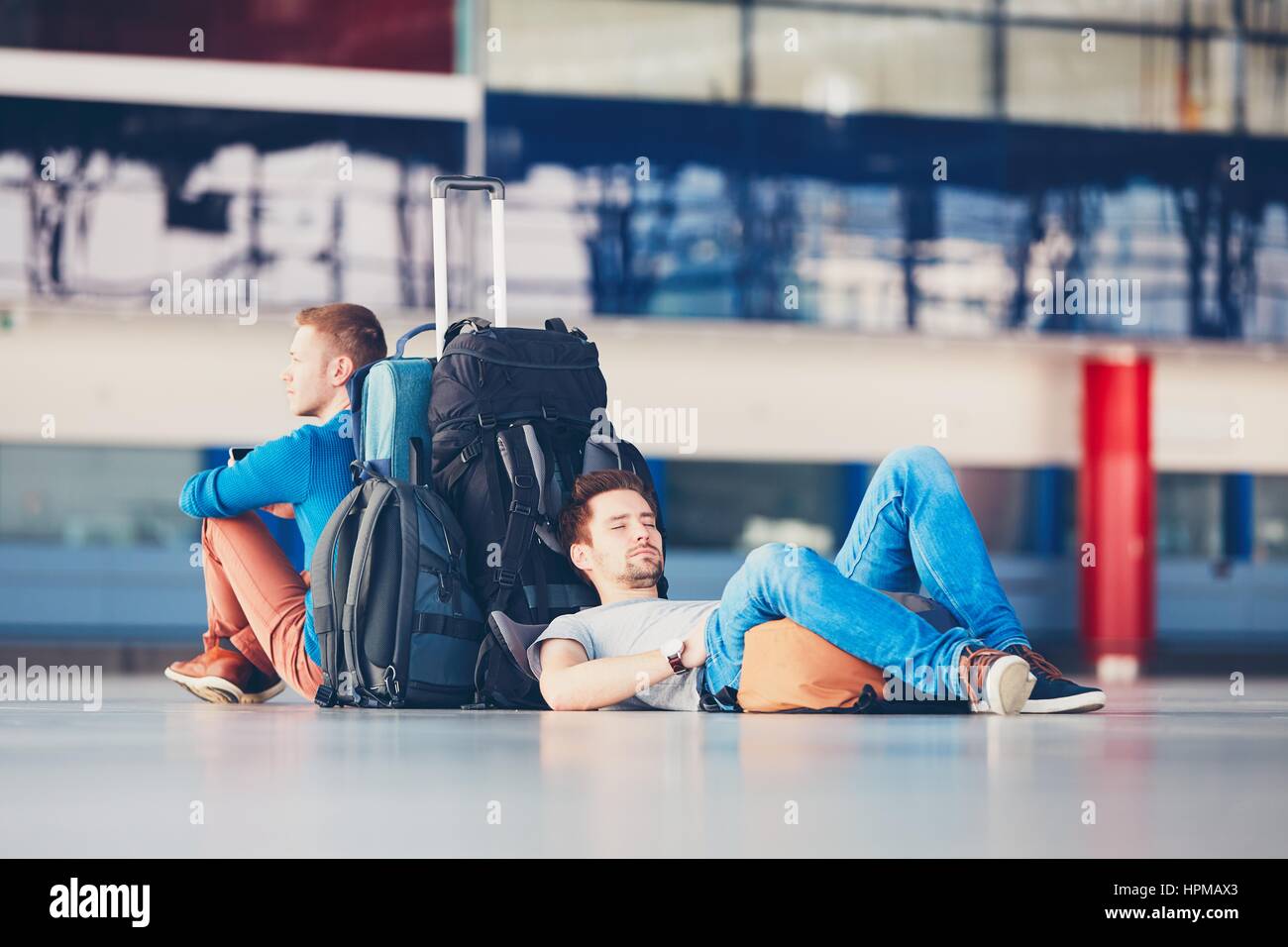 Zwei Freunde, die zusammen reisen. Reisende am Flughafen Abflugbereich für ihre Verspätung Flug warten. Stockfoto