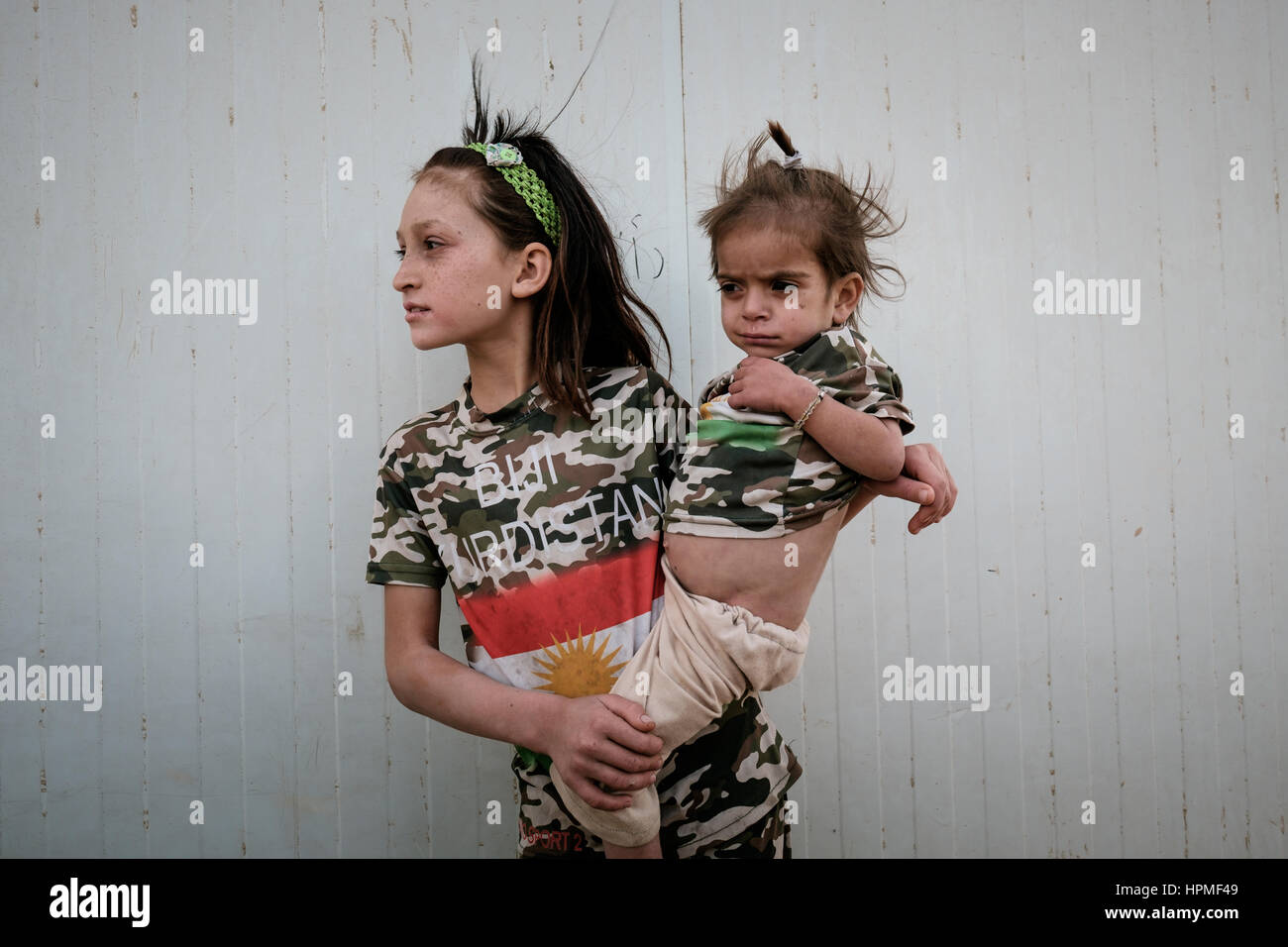 Ein junges Mädchen kann ihr Babyschwester T-Hemden mit Slogan BIJI KURDISTAN (lang lebe Kurdistan) außerhalb einer Schule in der Nähe von sunny, Irak Stockfoto