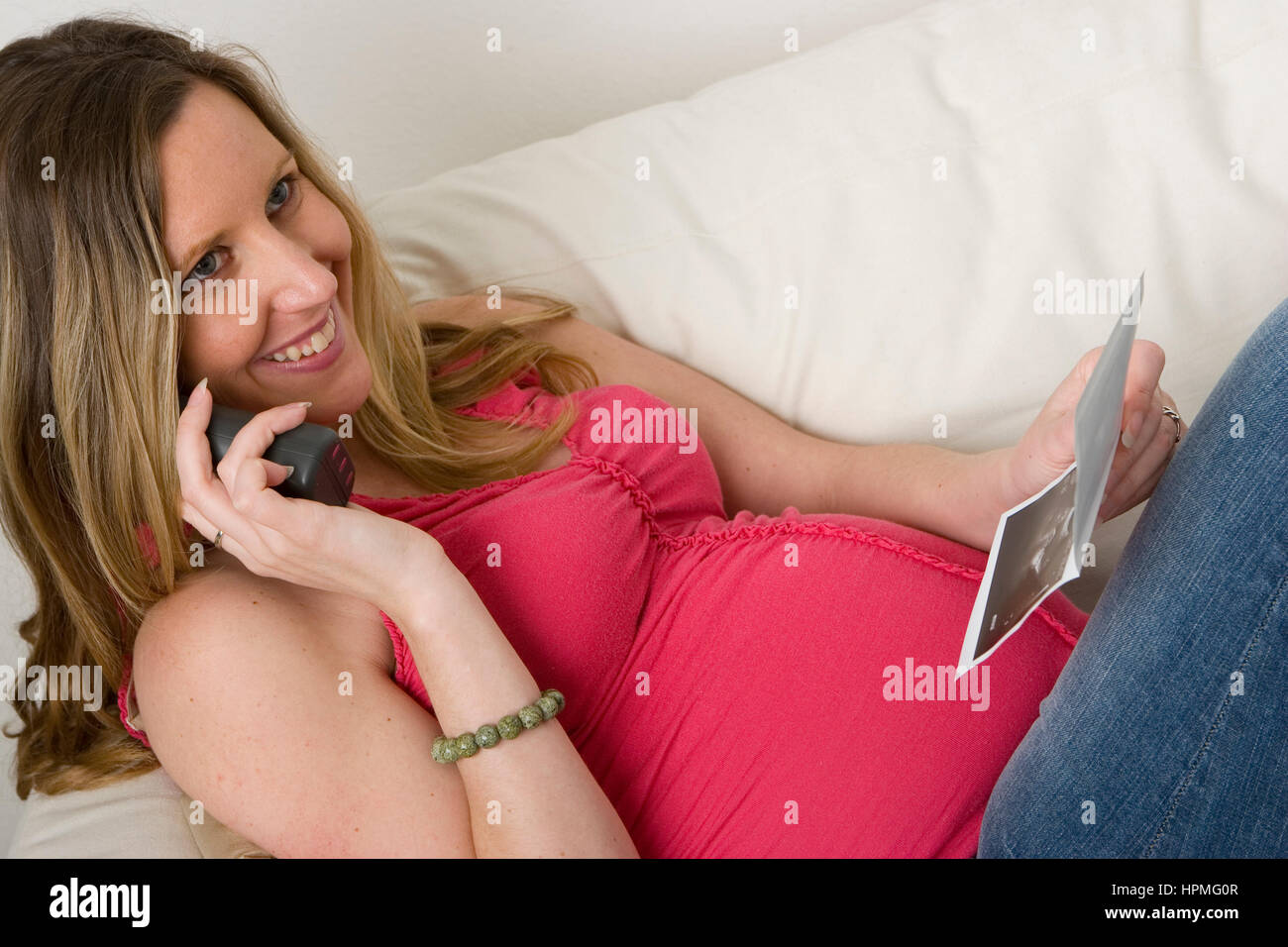 Schwangere Frau mit Blick auf eine Ultraschall-Foto ihres Babys Stockfoto
