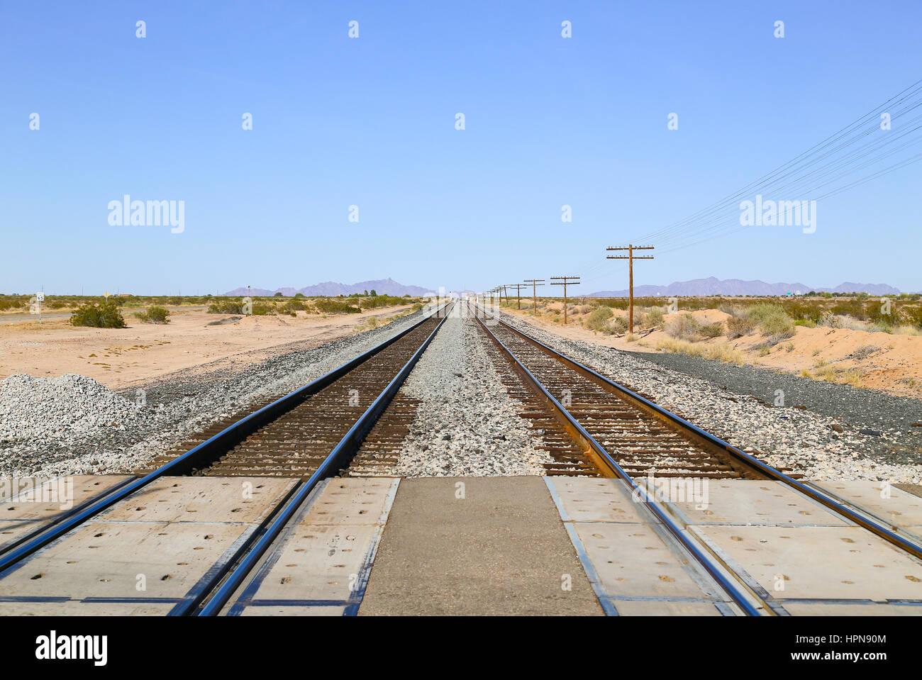 Eisenbahnschienen an einer Kreuzung in der Sonoran Wüste, Arizona, USA, mit Oberleitung Kabel auf der einen Seite und den alten uns Highway 80 zum anderen und eine Stockfoto