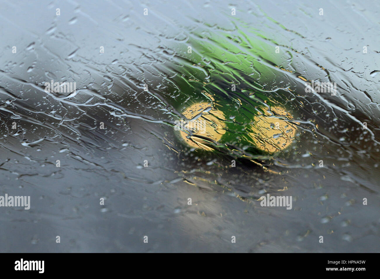 Scheinwerfer des entgegenkommenden Verkehrs durch Regen auf einer Windschutzscheibe gesehen Stockfoto