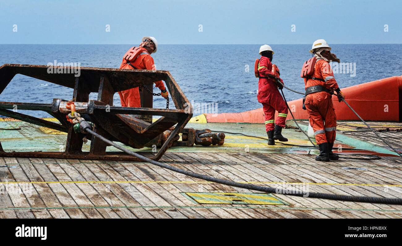 Offshore Arbeitnehmer Arbeiten an Deck tun Rigging umschlingen während Anker operation Job auf See Stockfoto