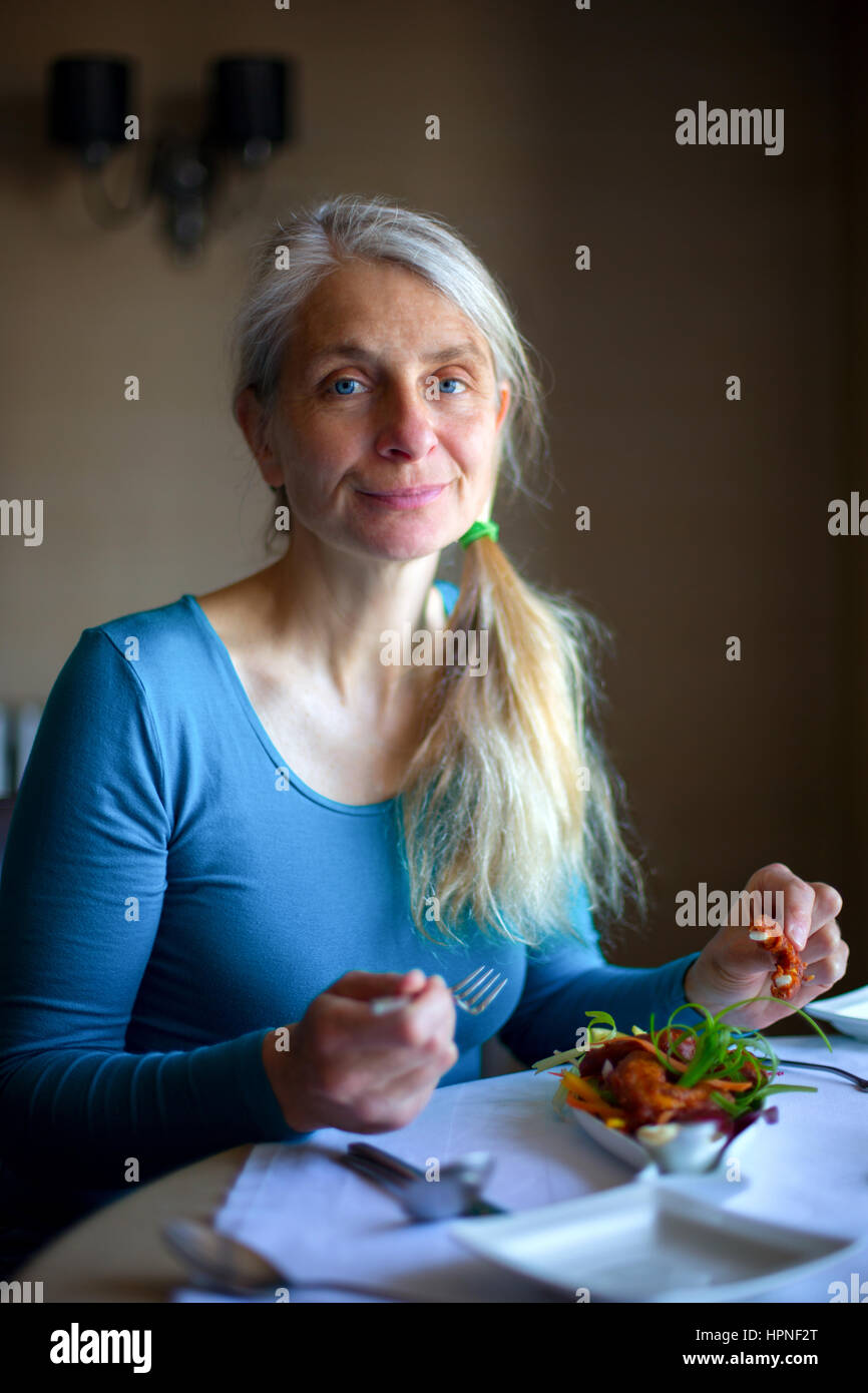 Porträt einer reifen Frau genießen Calamari Vorspeise Stockfoto
