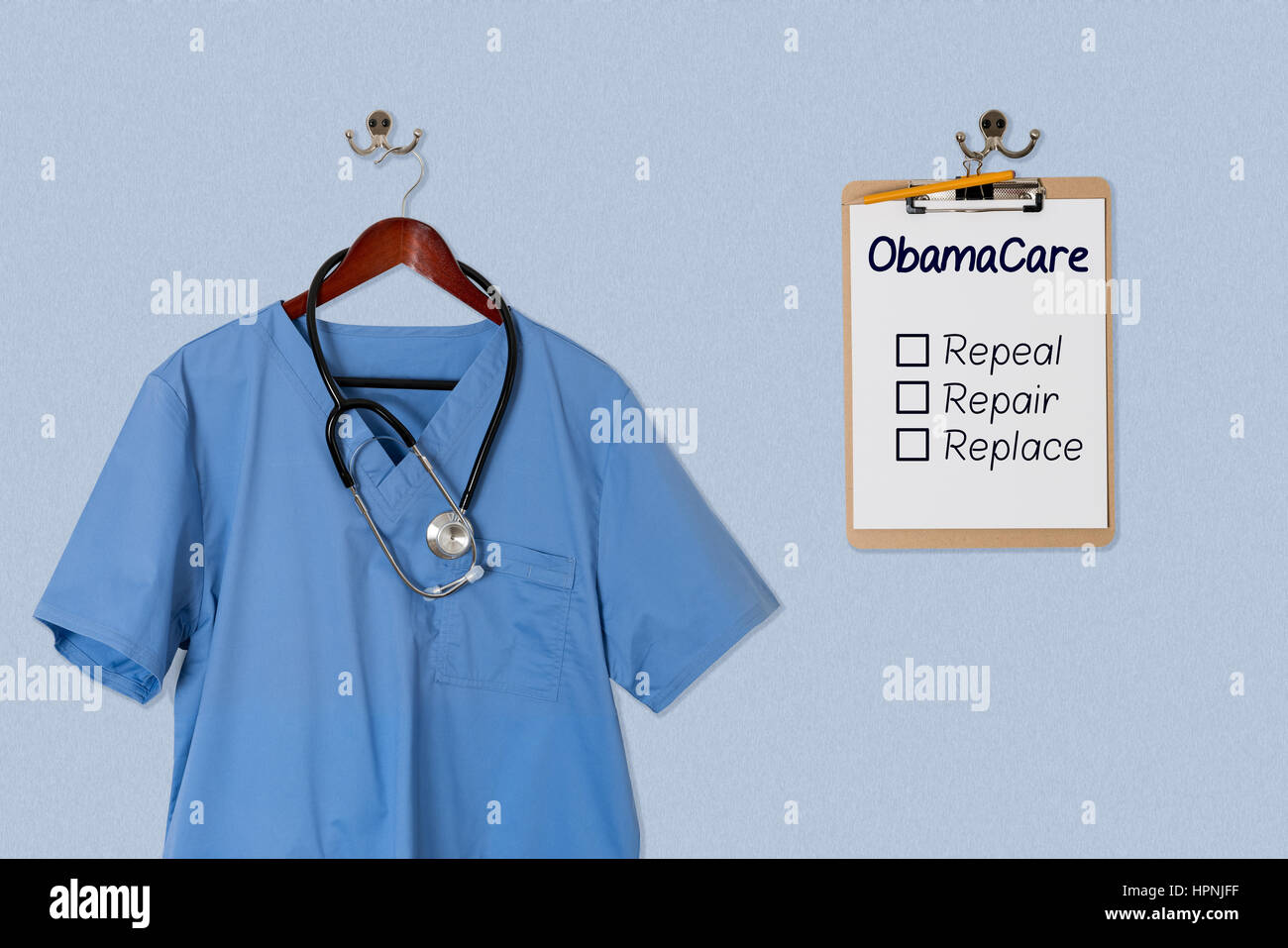 Blaue medizinische Peelings gleichmäßige Hemd hängend auf einem Kleiderbügel mit Stethoskop mit Obamacare Optionen in Zwischenablage Stockfoto