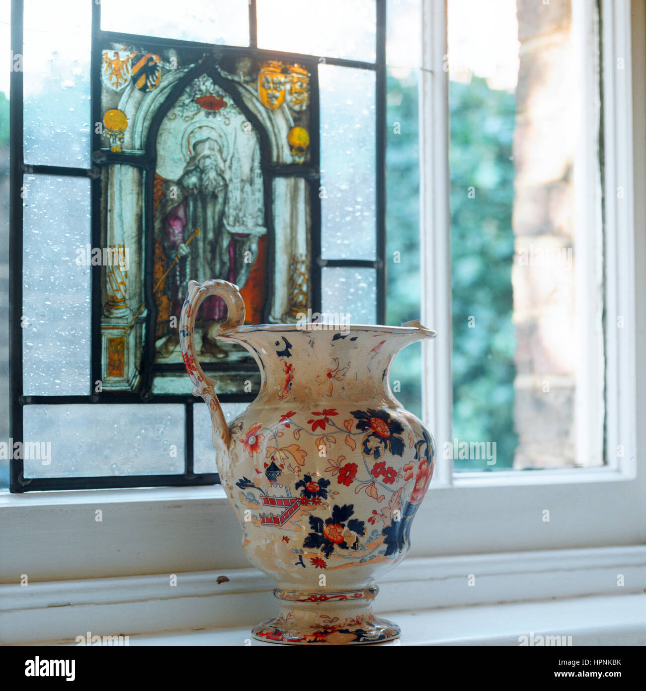 Eine Vase auf einer Fensterbank mit Buntglas. Stockfoto