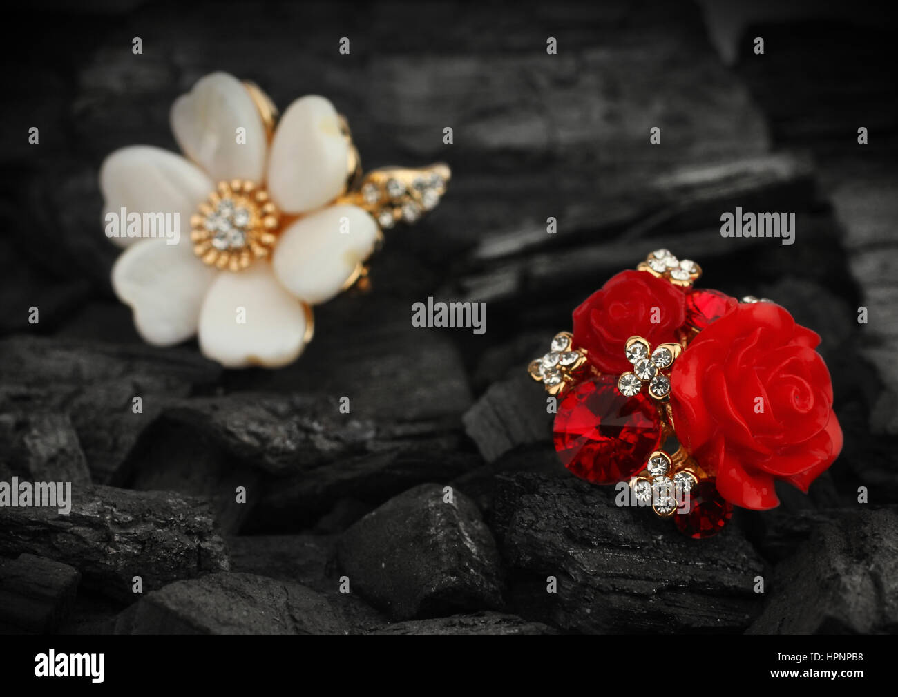 Paar Schmuck Ringe mit Diamanten, Edelsteinen und Perlen auf Steinkohle Hintergrund Stockfoto