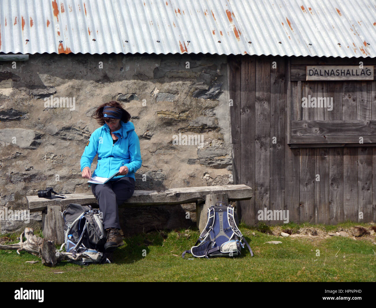 Einsame Frau saß auf Bank Buch Kommentare an Dalnashallag Schutzhütte in Glen Banchor auf dem Ost-Highland-Way in den schottischen Highlands, Schottland, Großbritannien. Stockfoto