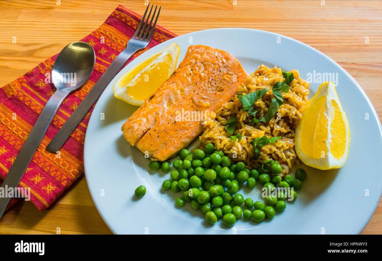 Pochierter Lachs mit braunem Reis, frischen grünen Erbsen, Kräutern und Zitrone. Stockfoto