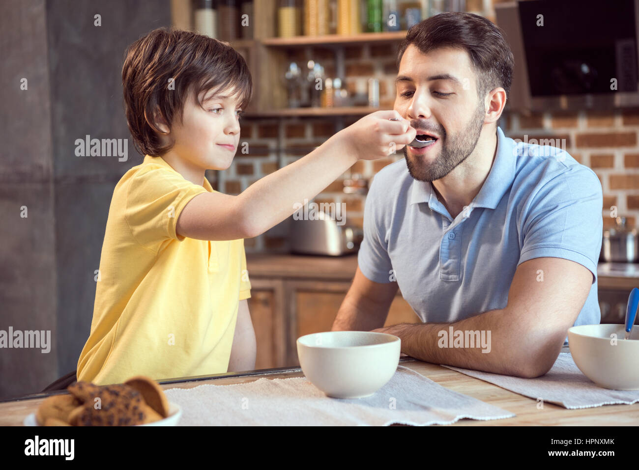 lächelnde junge Fütterung Vater mit Frühstück Stockfoto