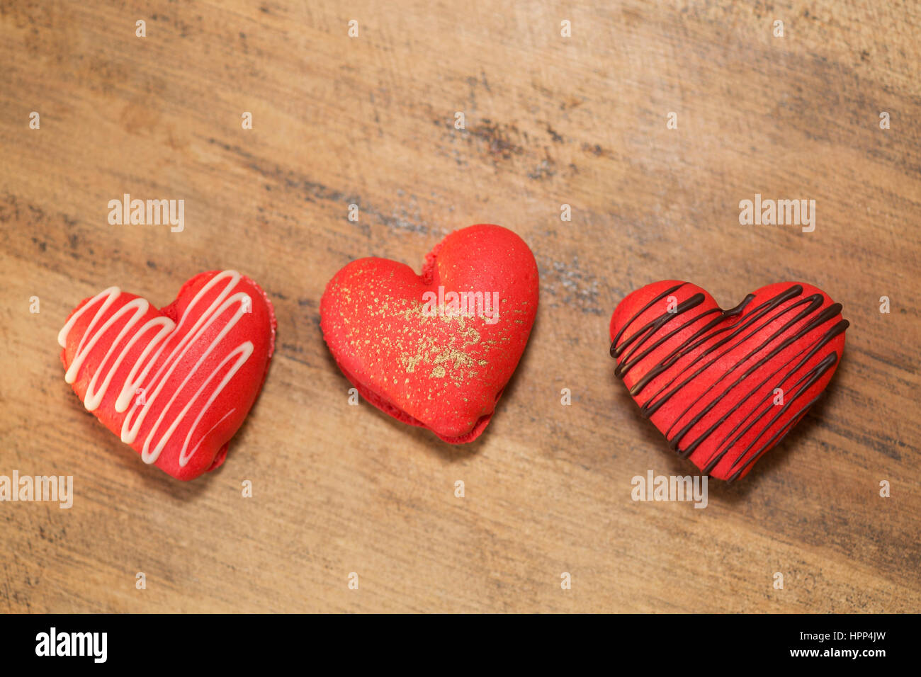 Herzförmige Erdbeermakronen, dekoriert mit Schokolade und Gold zum Valentinstag, auf Holzoberfläche Stockfoto