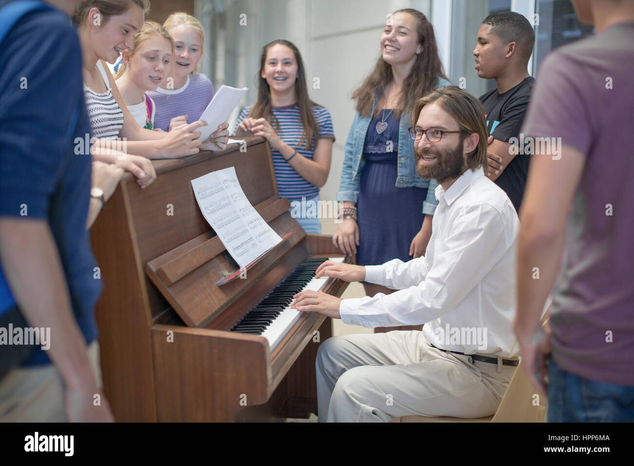 Lehrer mit Gruppe von Studenten, die herumstehen Klavier Stockfoto