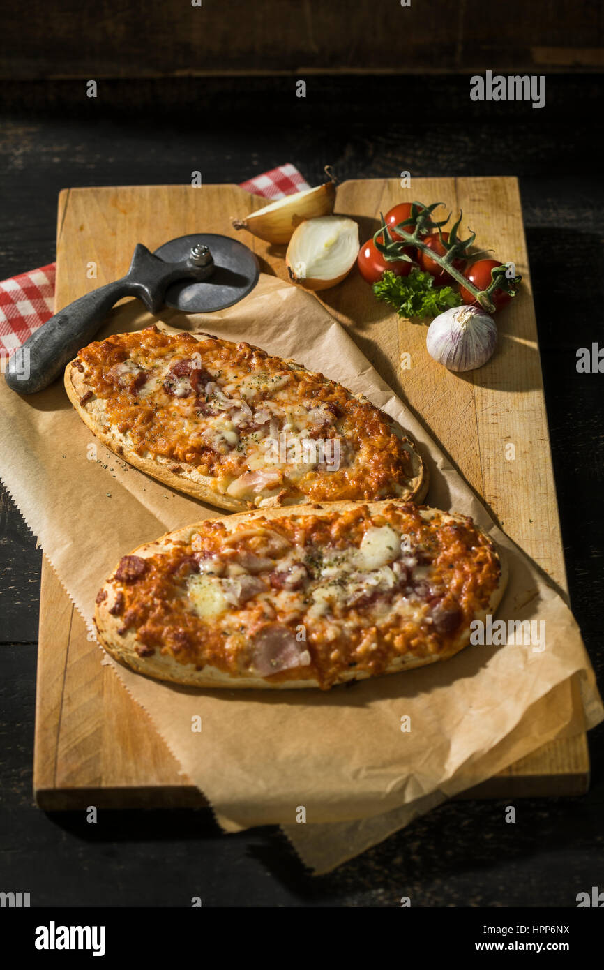 Zwei Pizza-Brot mit Tomaten, Zwiebeln, Salami und Käse Stockfoto