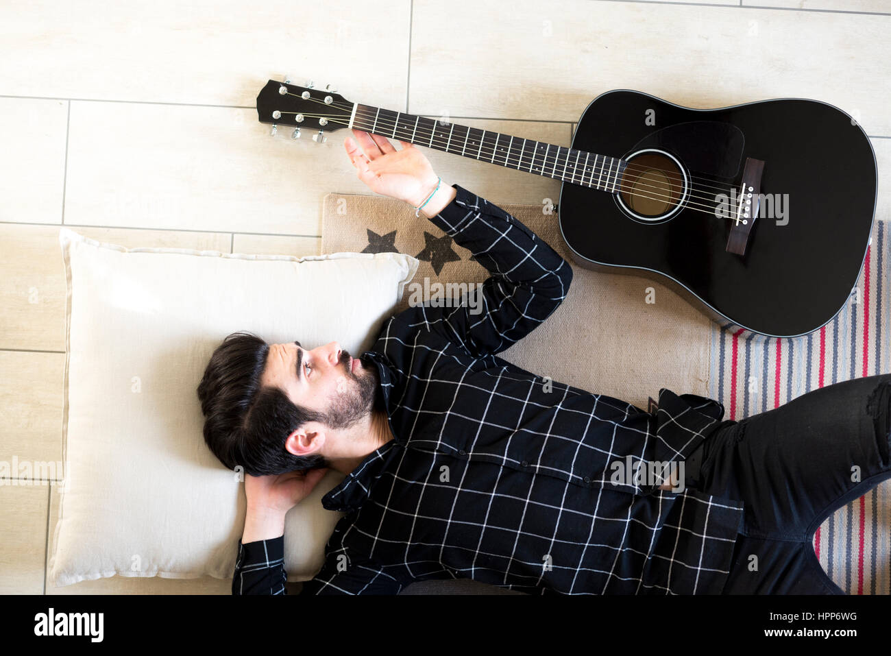 Junger Mann zu Hause liegen auf dem Boden neben Gitarre Stockfoto