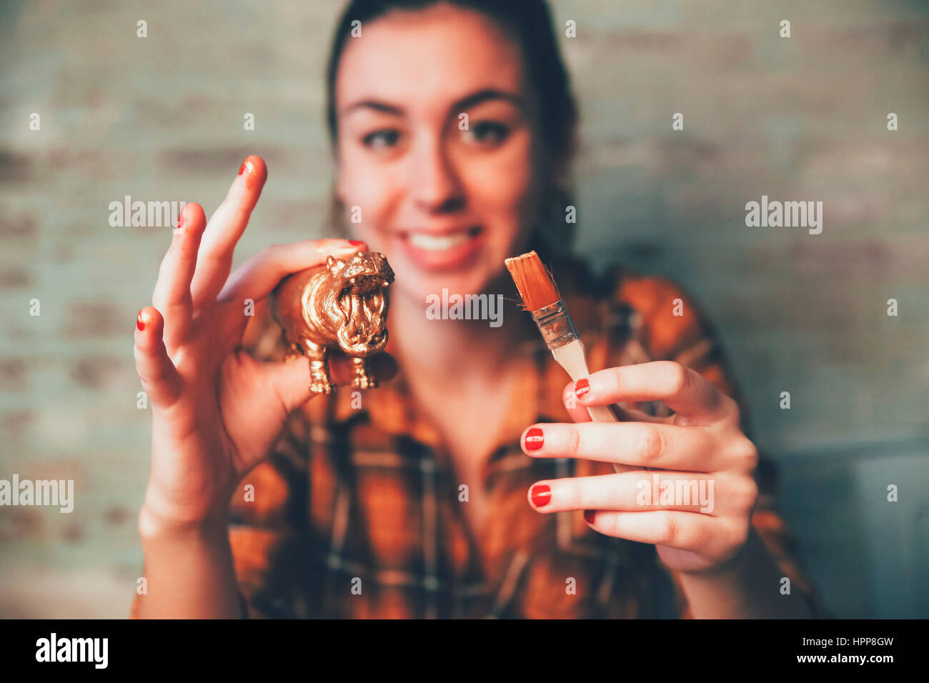 Junge Frau Malerei Nilpferd Plastikfigur mit Goldfarbe Stockfoto