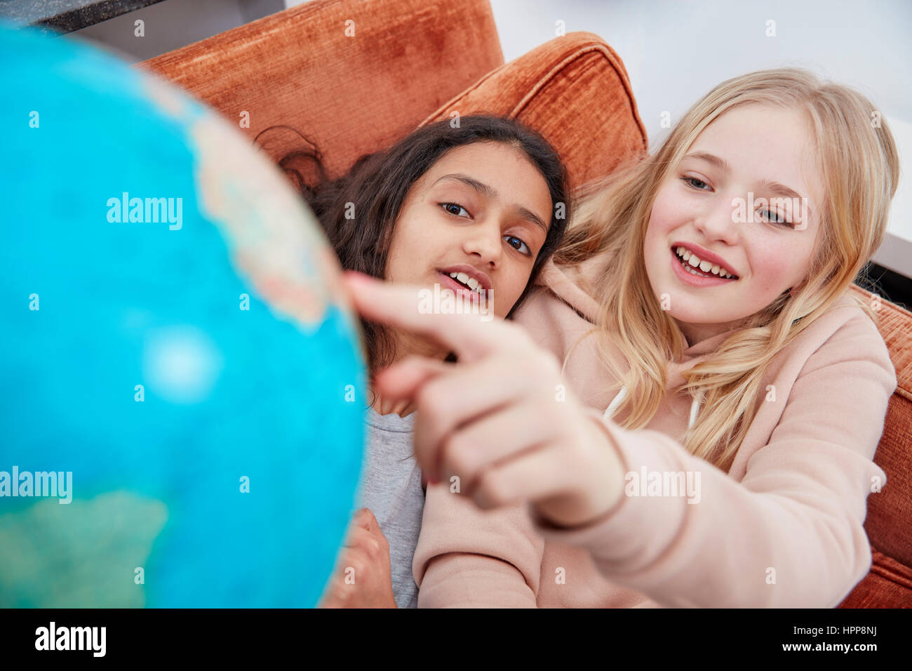 Zwei Mädchen auf Couch zeigt im globe Stockfoto
