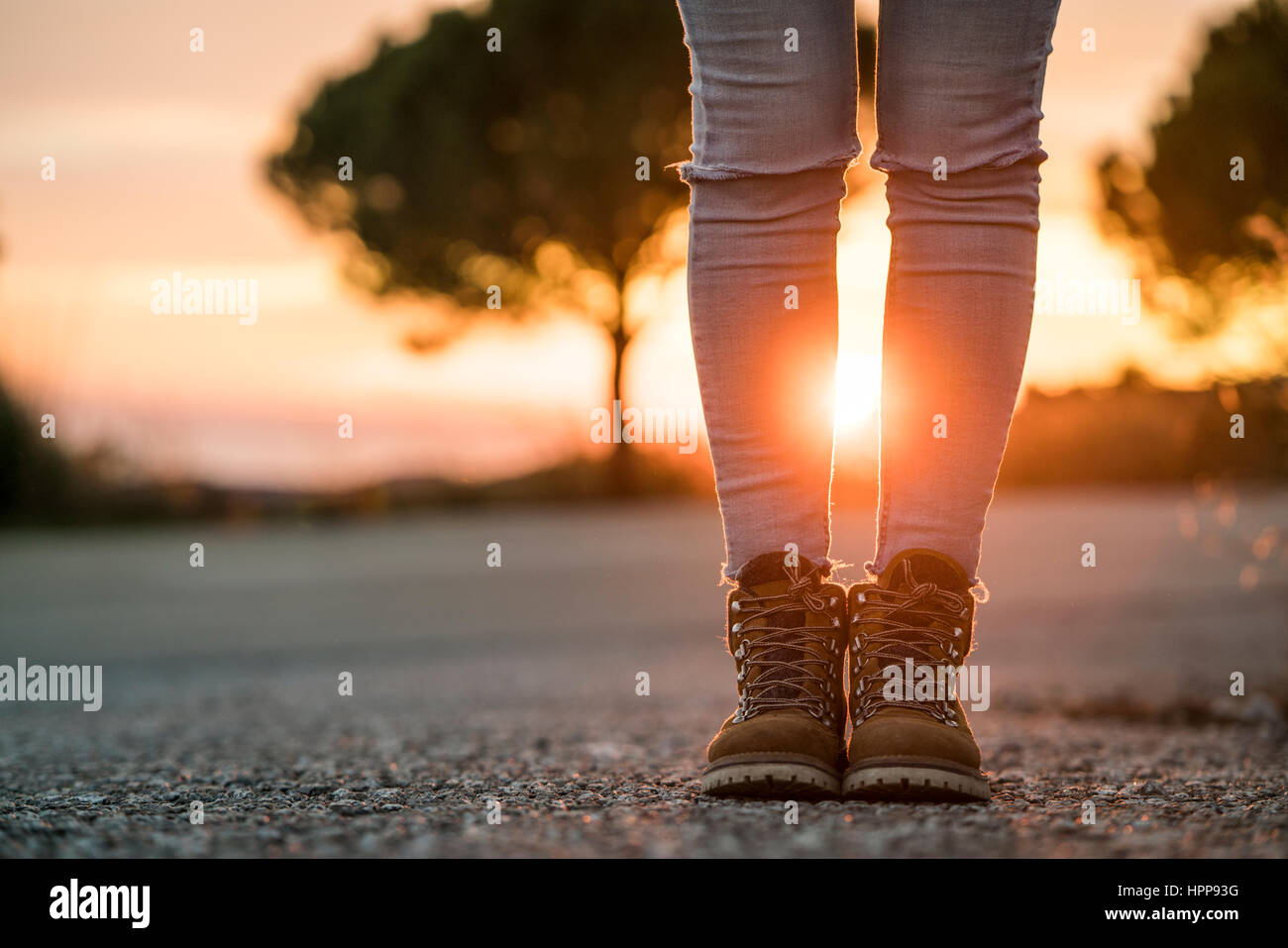 Frau trägt Wandern Stiefel stehen auf einer Straße bei Sonnenuntergang Stockfoto