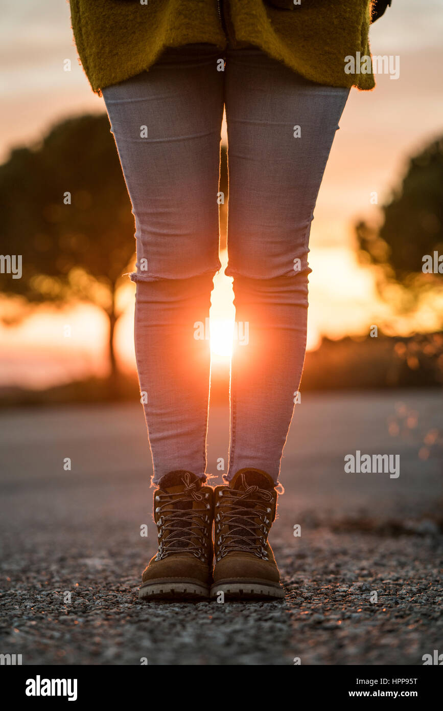 Frau trägt Wandern Stiefel stehen auf einer Straße bei Sonnenuntergang Stockfoto