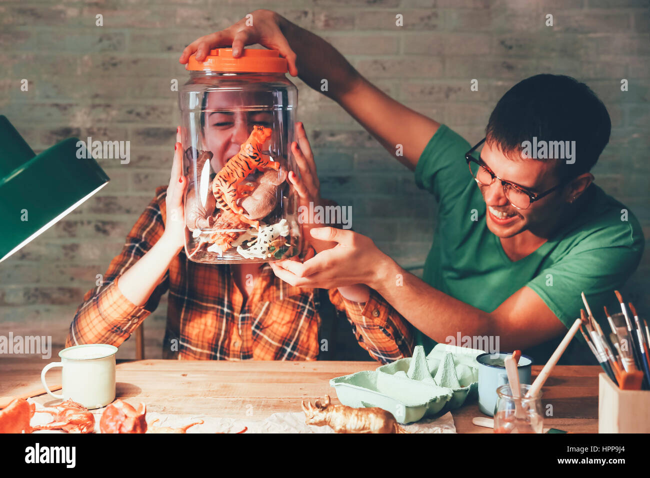 Junge Paare, die Spaß mit Tierfiguren in Glas Stockfoto