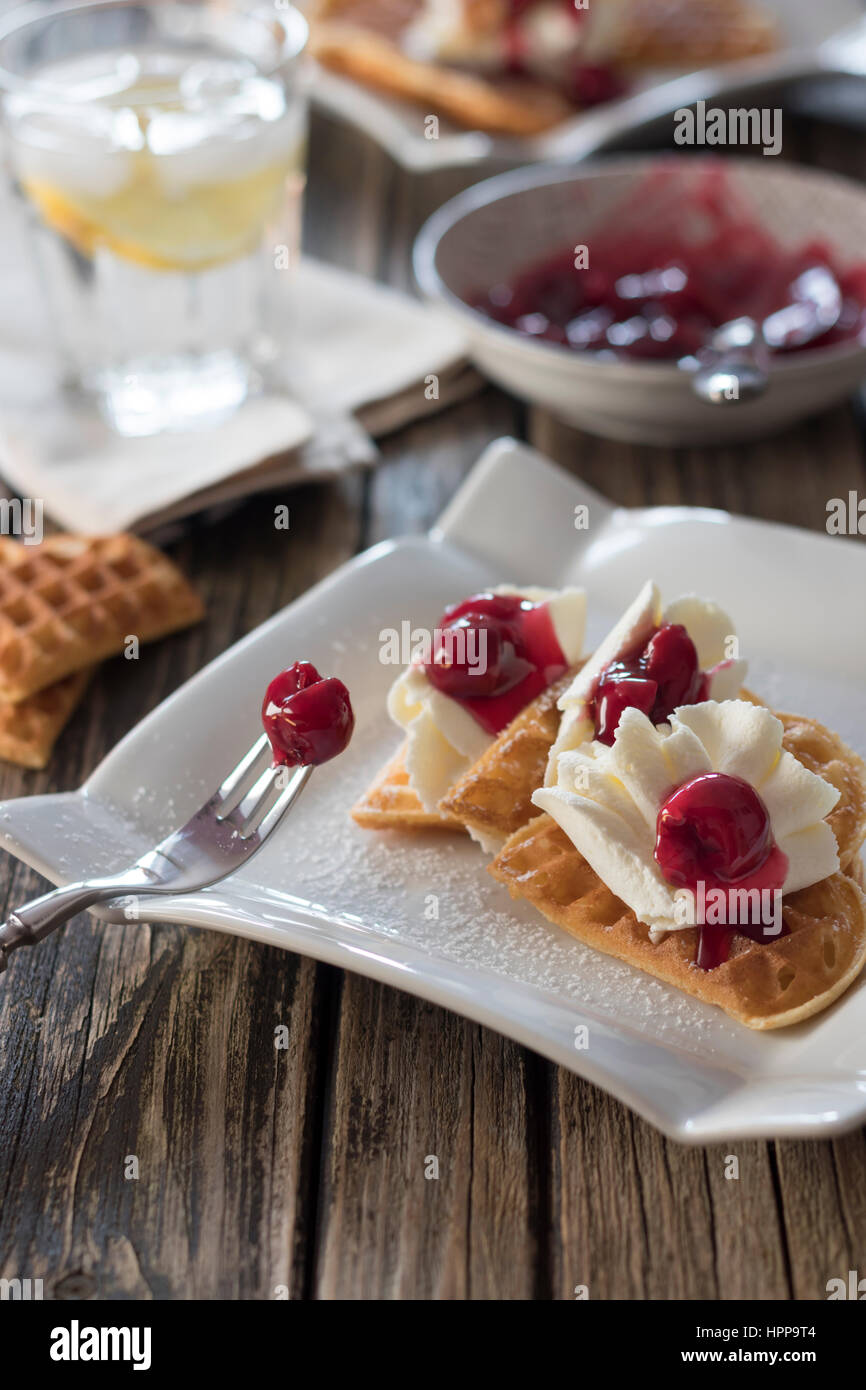 Teller mit Waffeln mit Schlagsahne, Kirschen und Kirsch Grütze Stockfoto