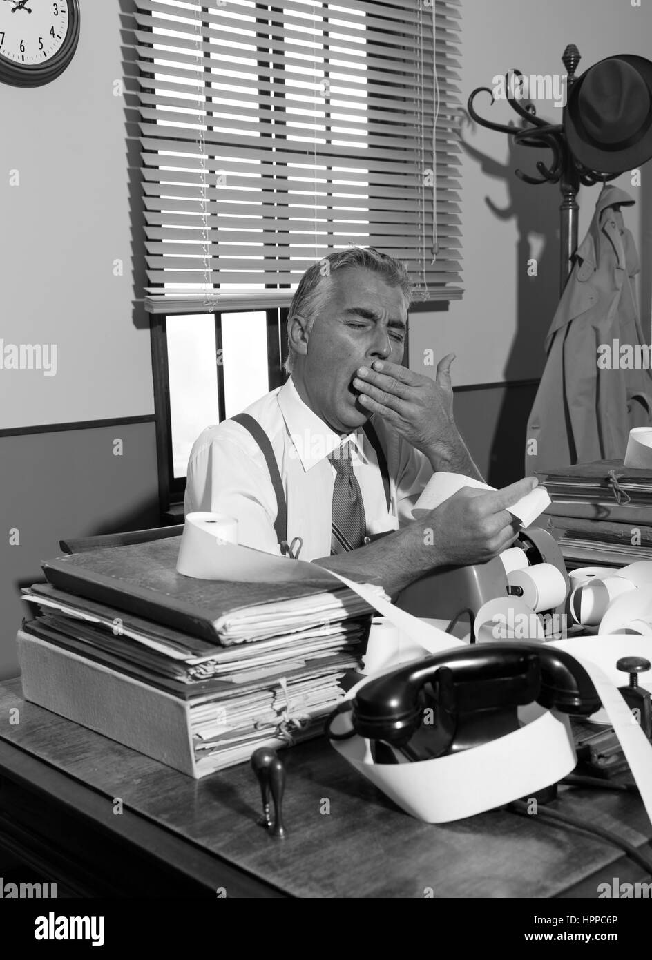 Müde Buchhalter Gähnen und Überprüfung von Rechnungen an seinem Schreibtisch, Vintage Büro. Stockfoto