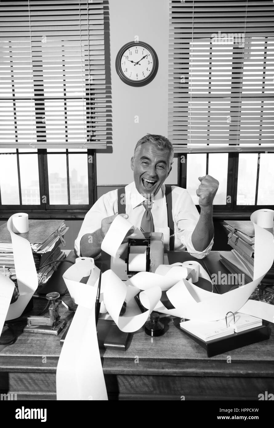 Fröhlichen Vintage Buchhalter umgeben durch Zugabe von Maschine-Papier-Klebeband in seinem Büro. Stockfoto