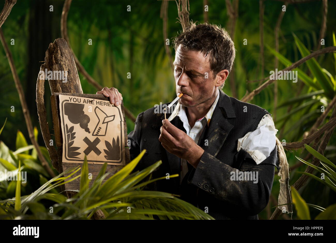 Geschäftsmann in Dschungel zündet sich eine Zigarette neben keine Rauchen Zeichen verloren. Stockfoto