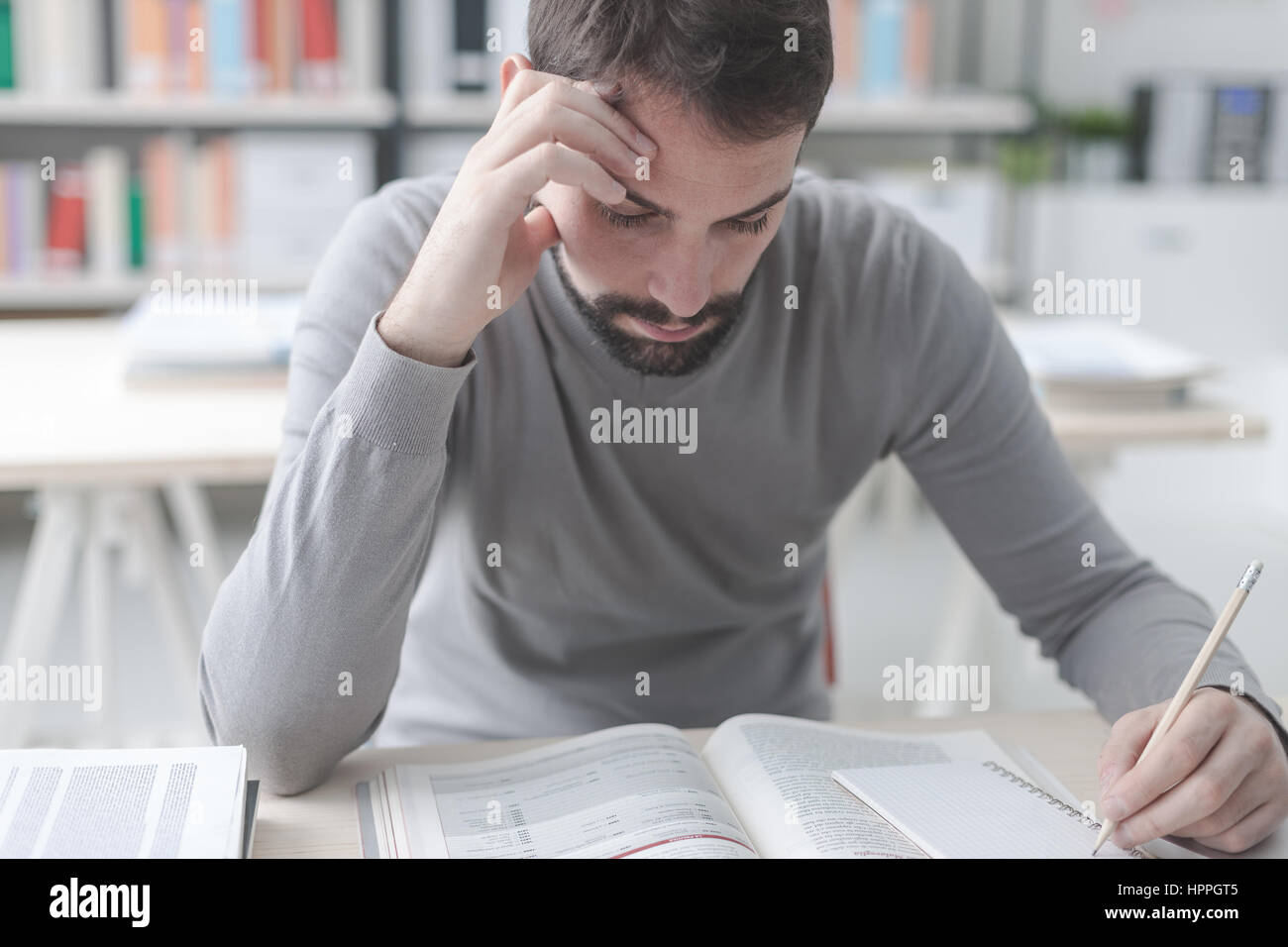 Erwachsener Mann am Schreibtisch sitzen und studieren an der Bibliothek konzentriert lernen und selbst-Verbesserung-Konzept Stockfoto