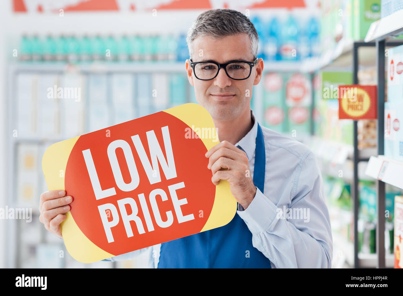 Zuversichtlich Supermarkt Schreiber mit einer Werbung Rabatt Schild, den Regalen auf dem Hintergrund Stockfoto