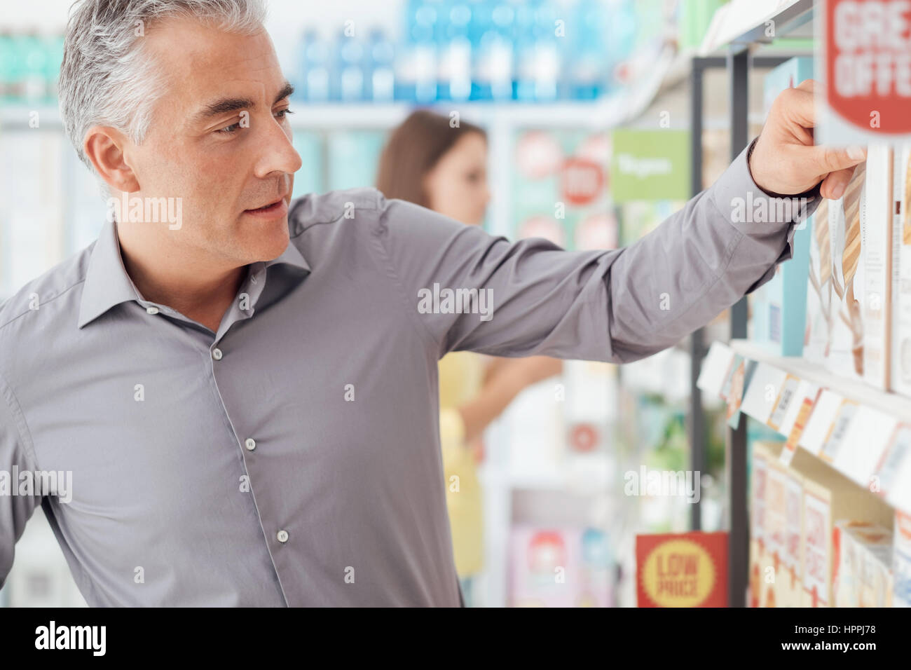 Mann tut Lebensmittelgeschäft Einkaufen im Supermarkt, er sucht Produkte im Verkaufsregal Stockfoto