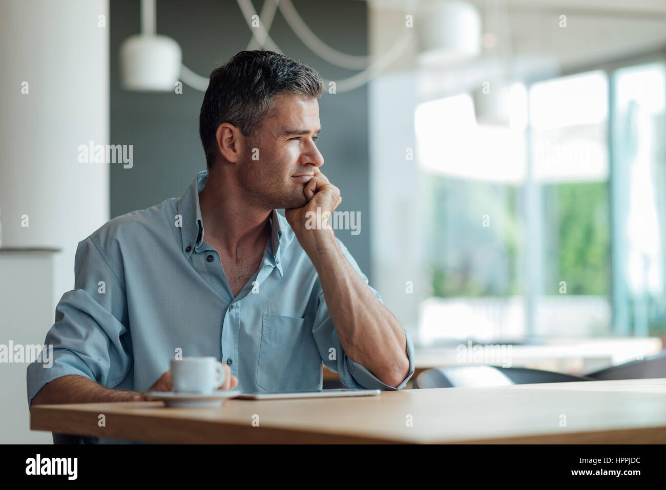 Unternehmer haben eine Kaffee-Pause an der Bar, er denkt mit Hand am Kinn, unter Verwendung einer digitalen-Tablets und Blick durch ein Fenster Stockfoto