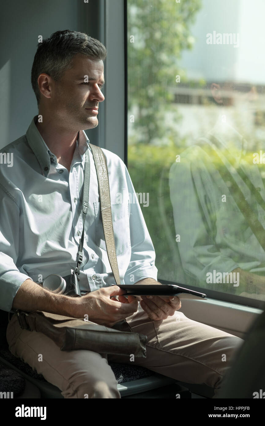 Mann, Reisen mit dem Bus und mit einem digital-Tablette, er arbeitet und Blick durch ein Fenster Stockfoto