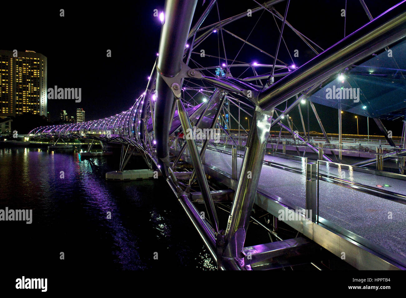 Eine abstrakte Sicht auf die Helix Brücke Fußgängerzone nachts in Singapur zeigt seine zeitgenössische neue röhrenförmige Stahlkonstruktion. Stockfoto