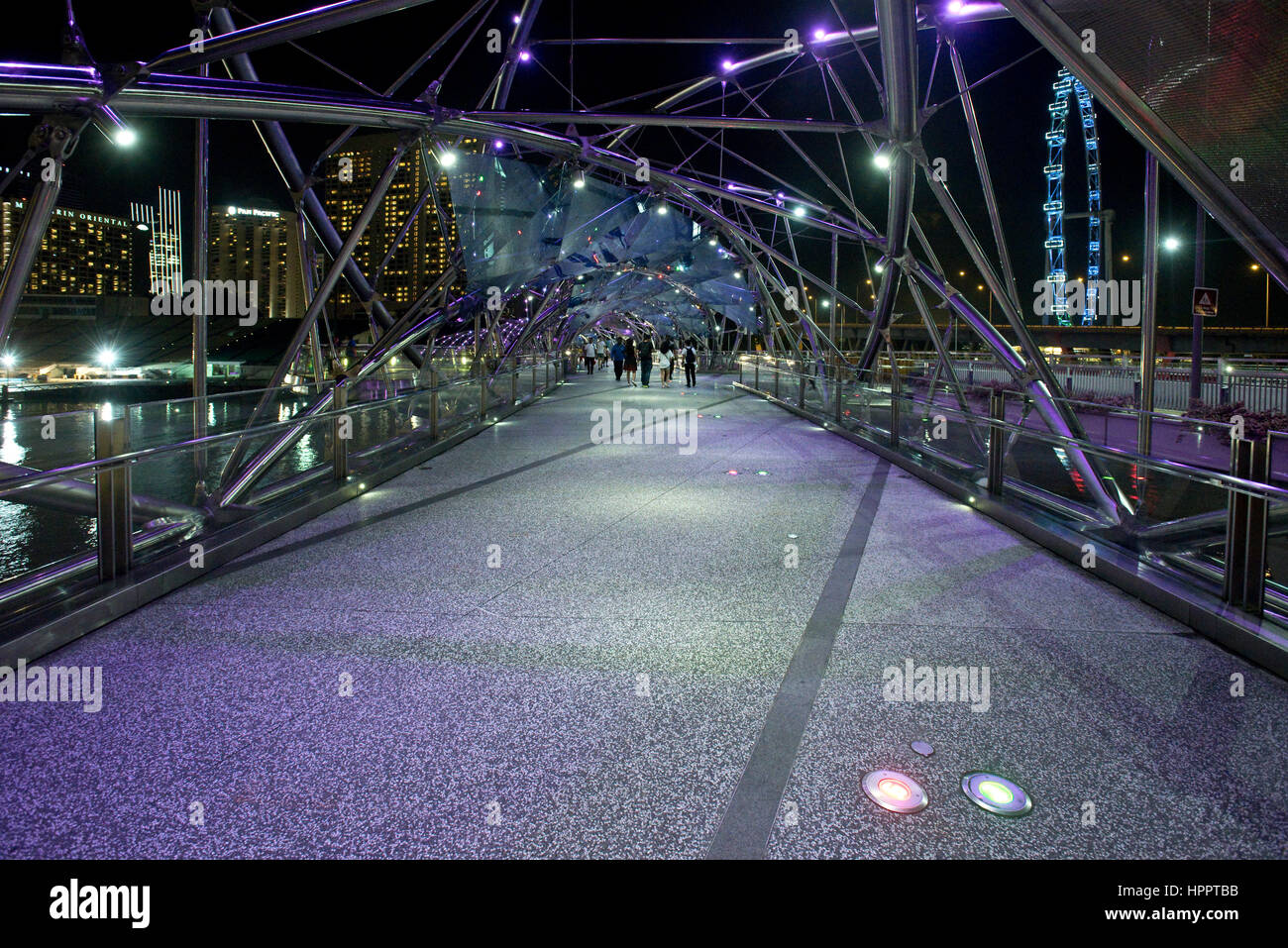 Eine abstrakte Sicht auf die Helix Brücke Fußgängerzone nachts in Singapur zeigt seine zeitgenössische neue röhrenförmige Stahlkonstruktion. Stockfoto