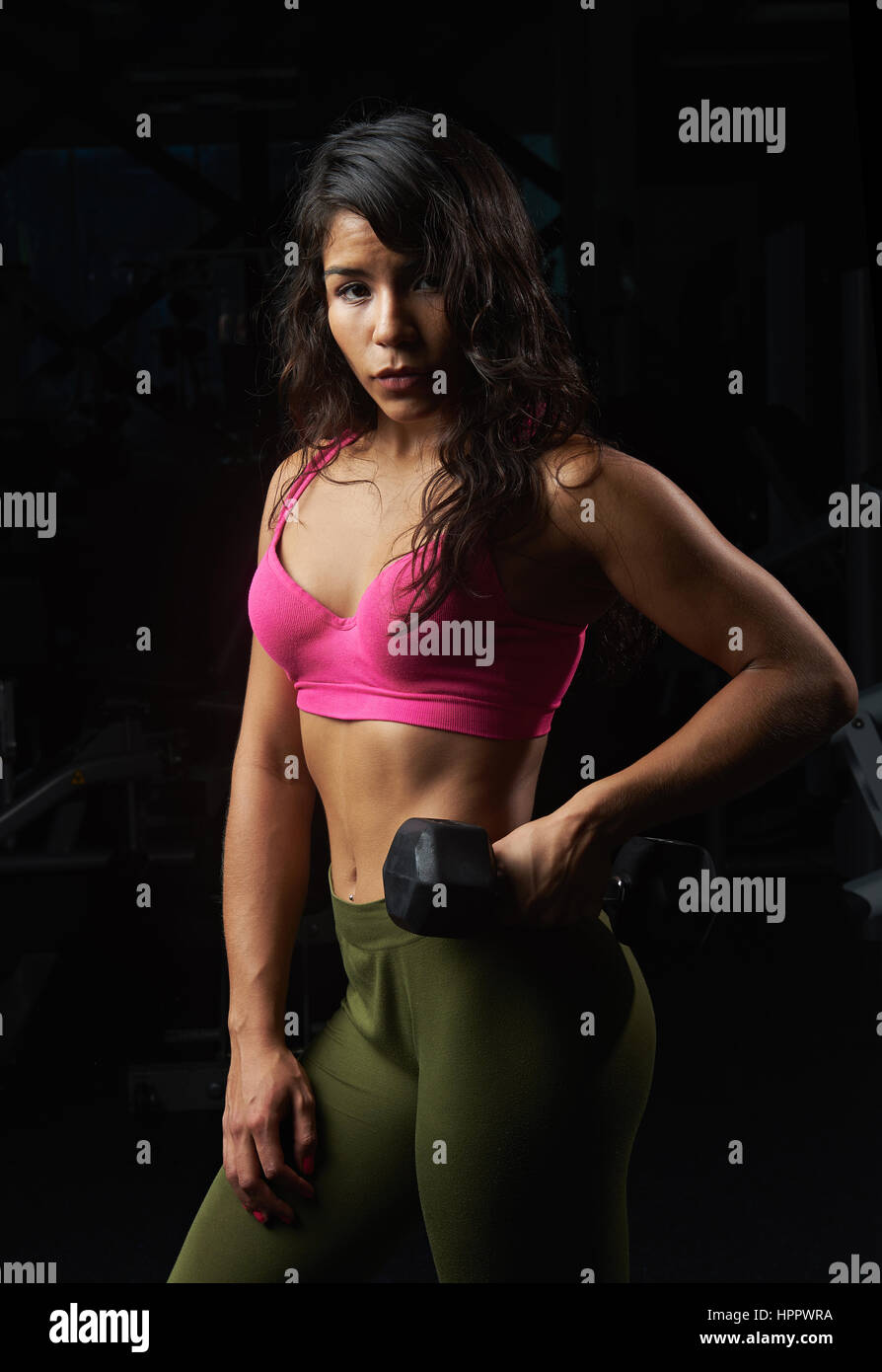 In guter Verfassung Mädchen mit Hantel auf schwarzem Hintergrund isoliert. Hispanischen Mädchen Training im modernen Fitness-club Stockfoto