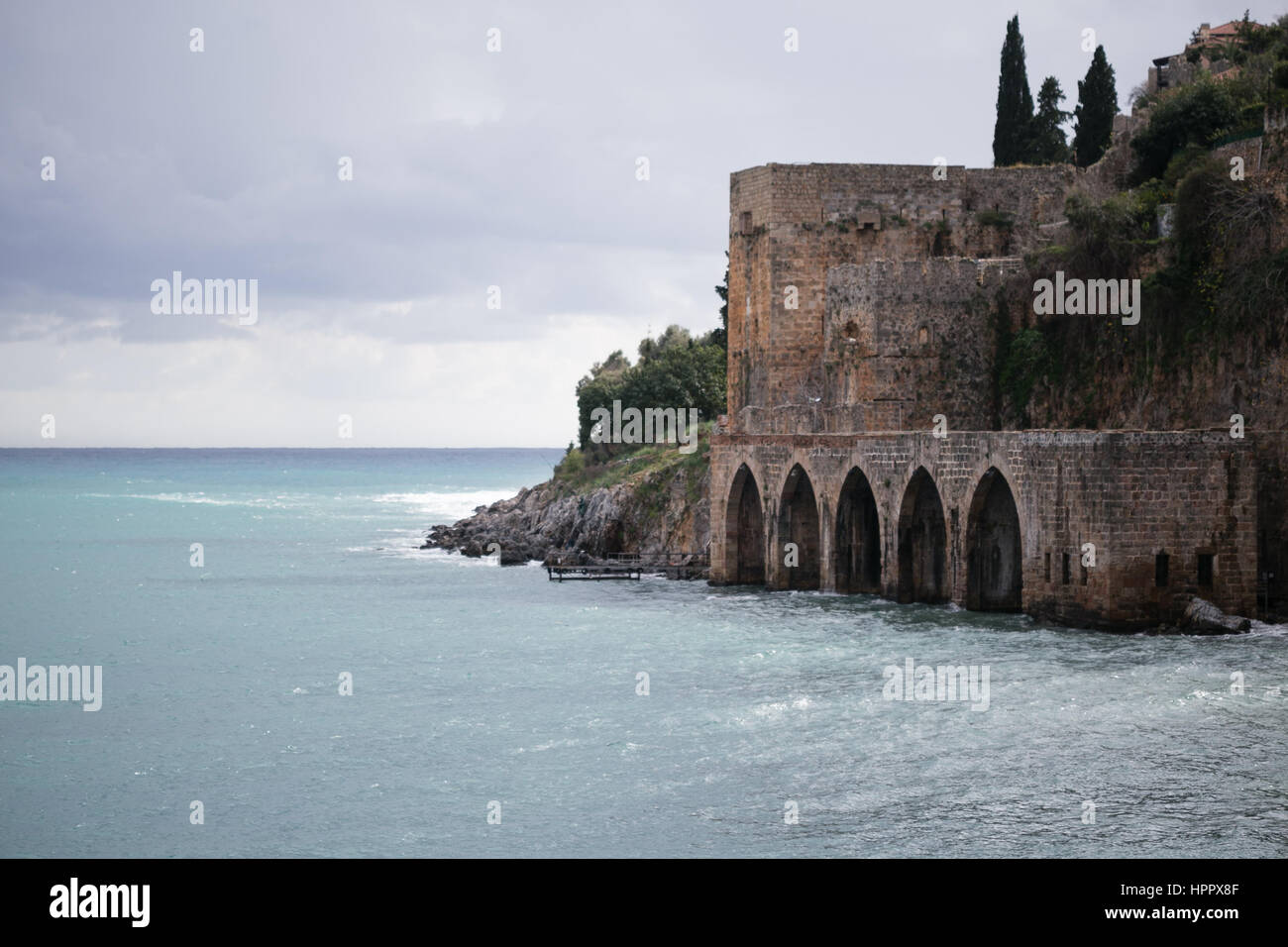 Mittelalterliche Werft mit Bögen und überragt es in mediterranen Stadt Alanya mit dramatischen grauen Wolken Schuss an Wintertag Stockfoto