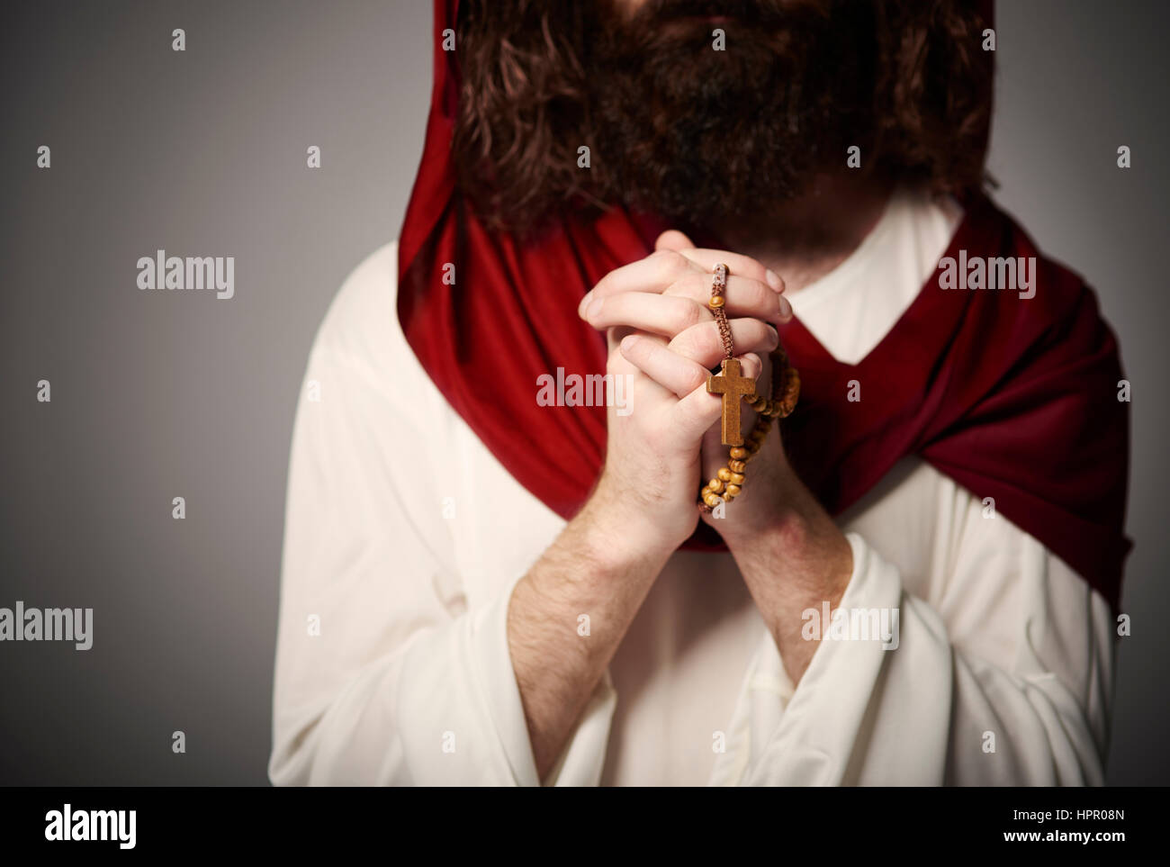 Jesus mit gefalteten Händen und Rosenkranz Stockfoto