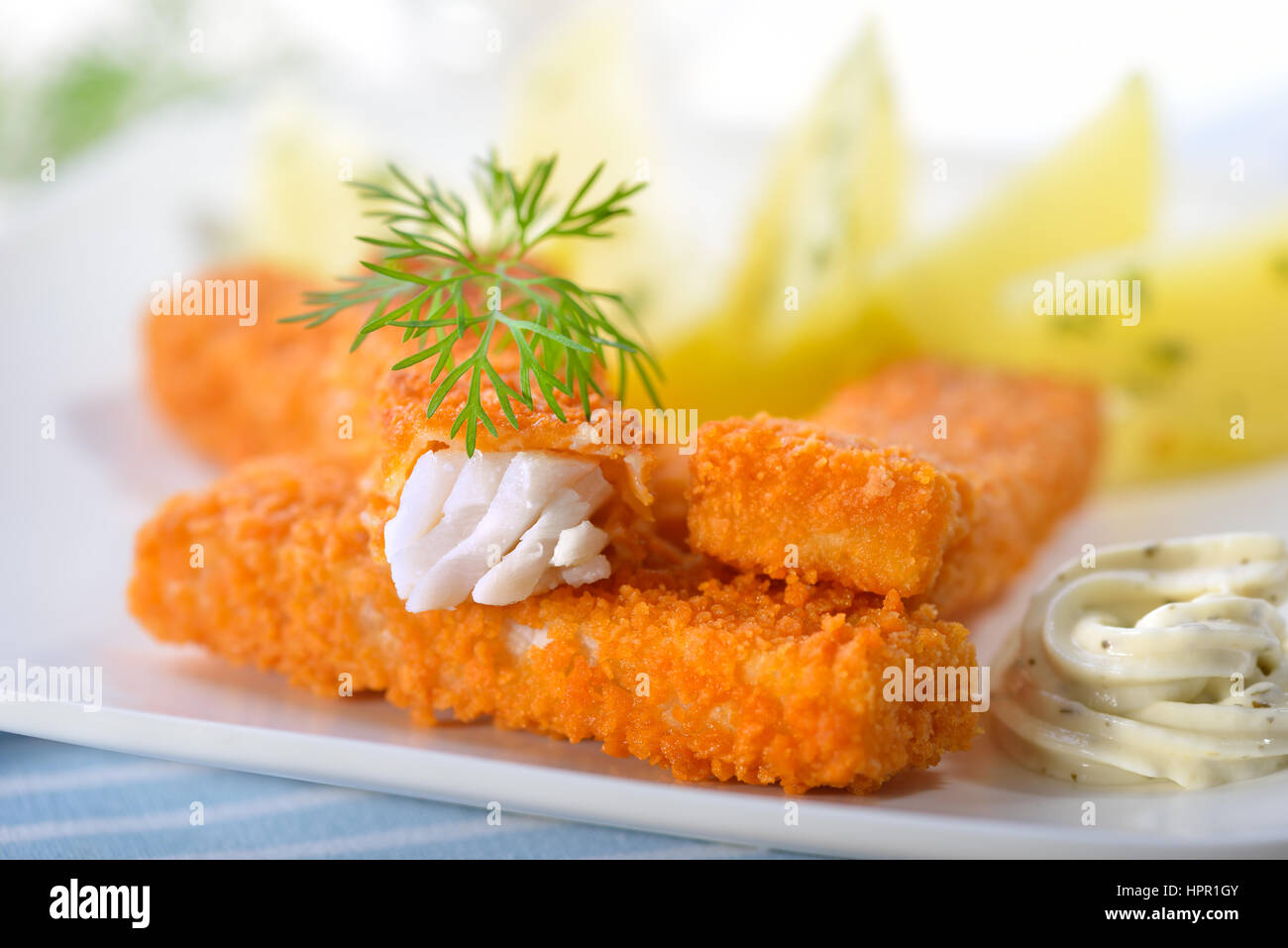 Knusprige Fischstäbchen panierte Seelachs-Filet serviert mit Petersilienkartoffeln und Sauce Remoulade auf einem weißen Teller - selektiven Fokus Stockfoto