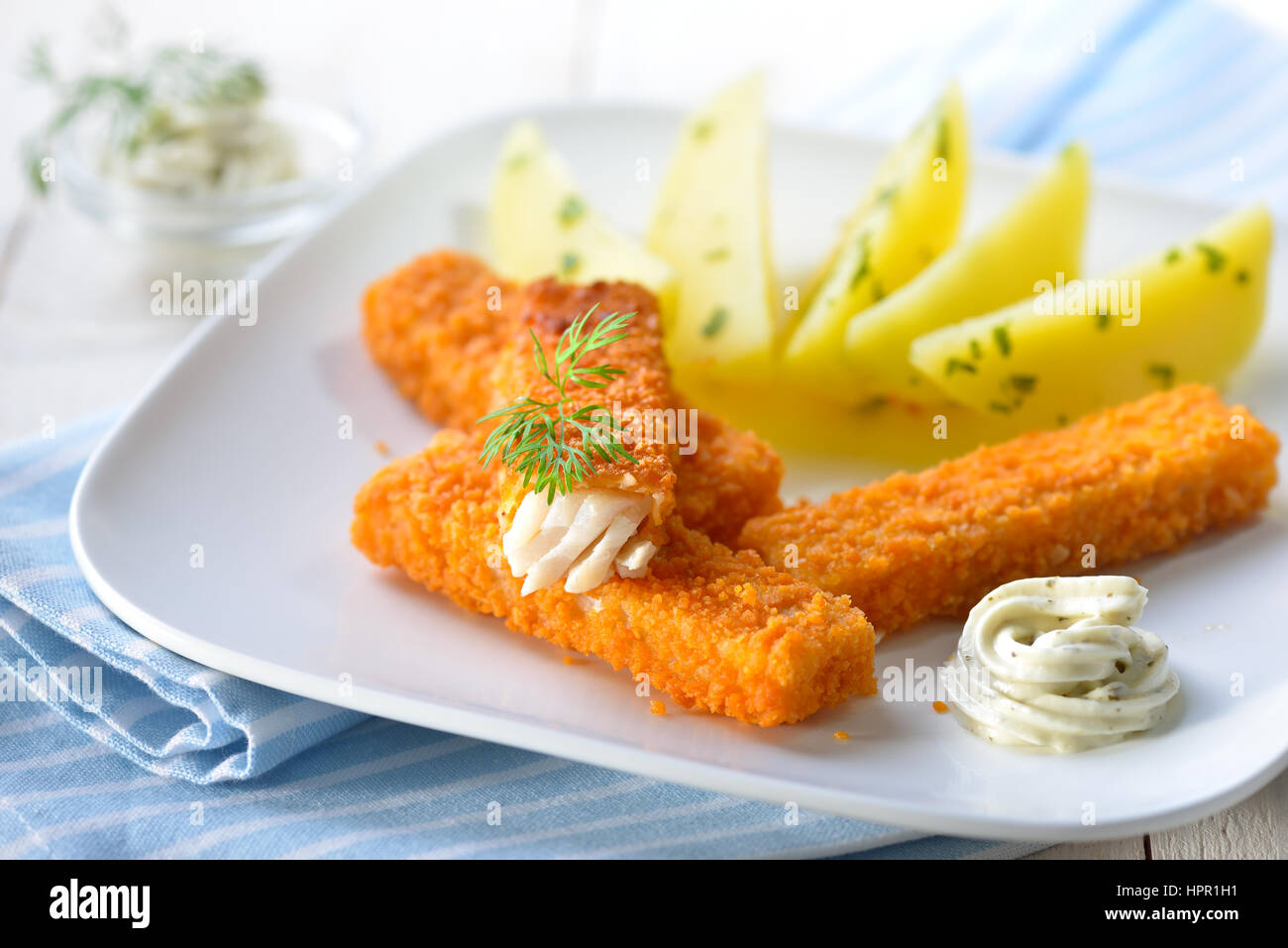 Knusprige Fischstäbchen panierte Seelachs-Filet serviert mit Petersilienkartoffeln und Sauce Remoulade auf einem weißen Teller - selektiven Fokus Stockfoto