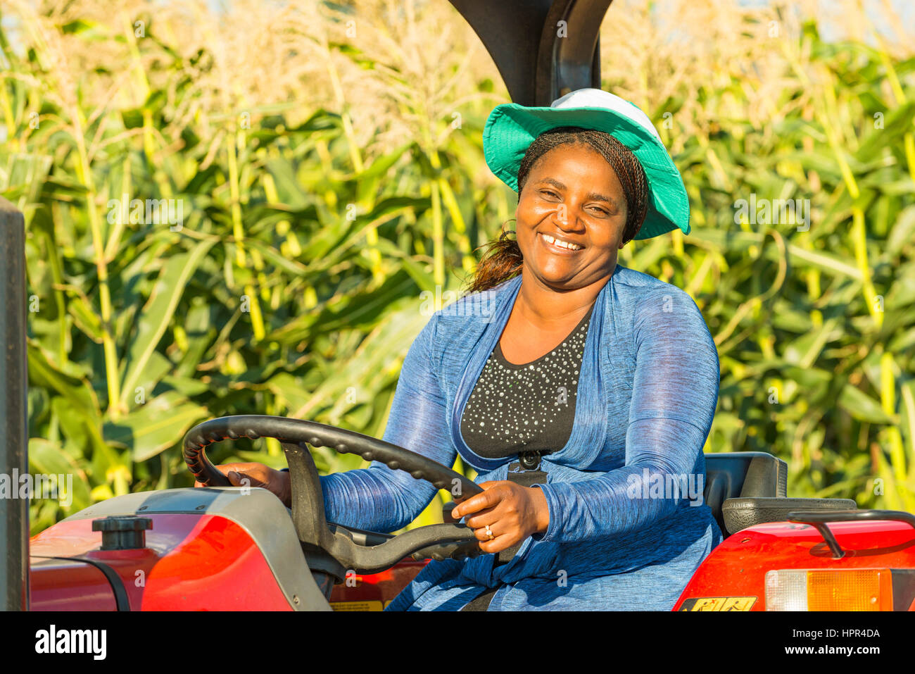 Eine lächelnde Frau sitzt auf einem Traktor in Simbabwe. Stockfoto
