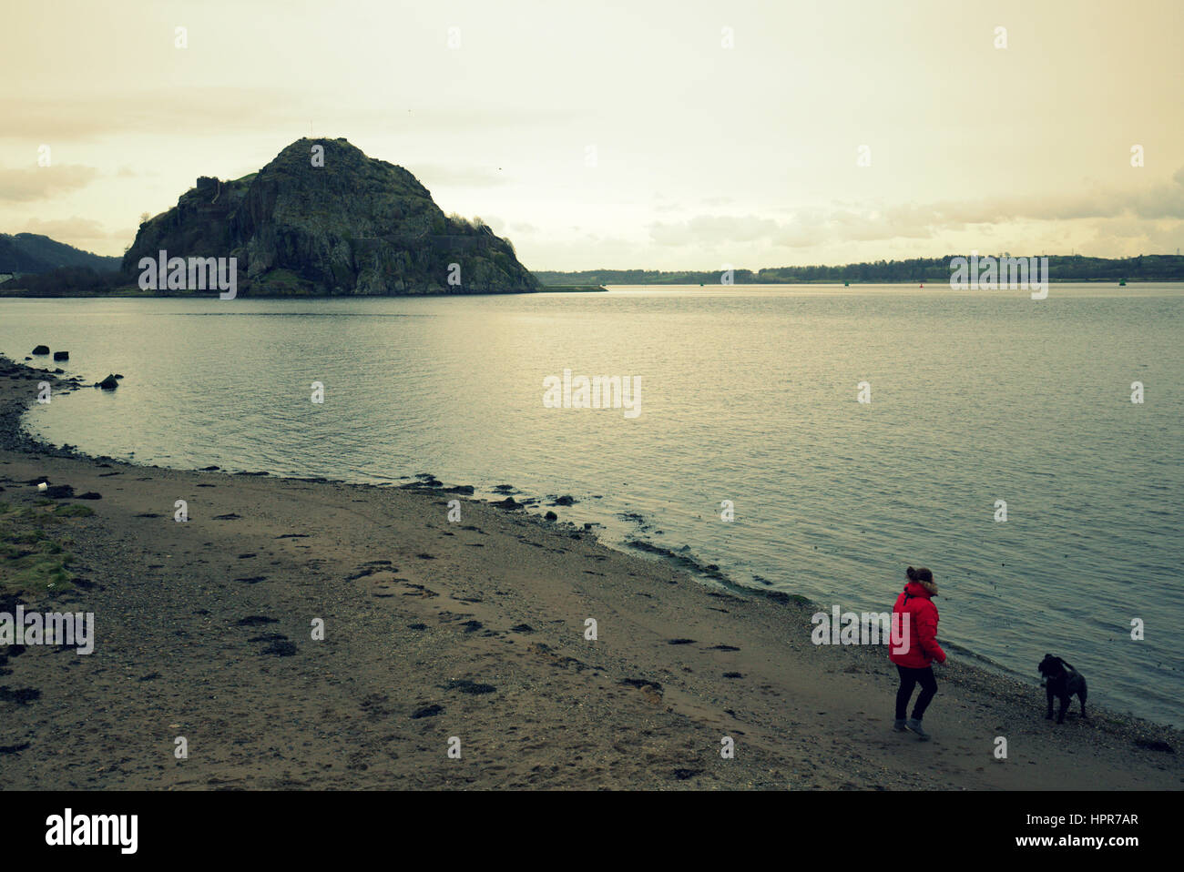 Dumbarton Castle Rock angesehen vom Ufer auf Leven Park Frau zu Fuß Hund am Ufer Stockfoto