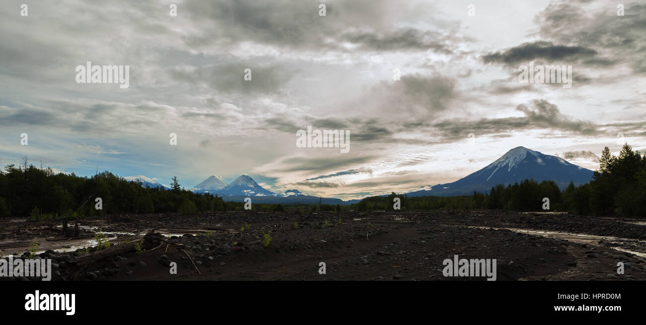 Sicht auf den Vulkan: Ostry Tolbachik, Klyuchevskaya Sopka, Besymjanny Kamen vom Fluss Studenaya in der Morgendämmerung. Kamtschatka-Halbinsel. Stockfoto