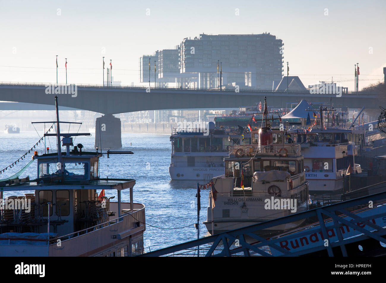 Deutschland, Köln, Ausflugsschiffe an den Ufern des Rheins. Im Hintergrund der Deutzer Brücke und der Kran Häuser im Rheinau-Hafen. Stockfoto