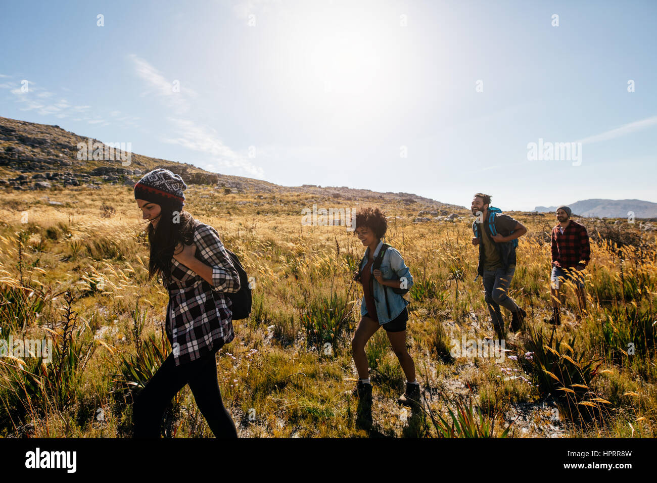 Gruppe von Jugendlichen auf Land zu Fuß. Junge Männer und Frauen wandern an einem Sommertag. Stockfoto