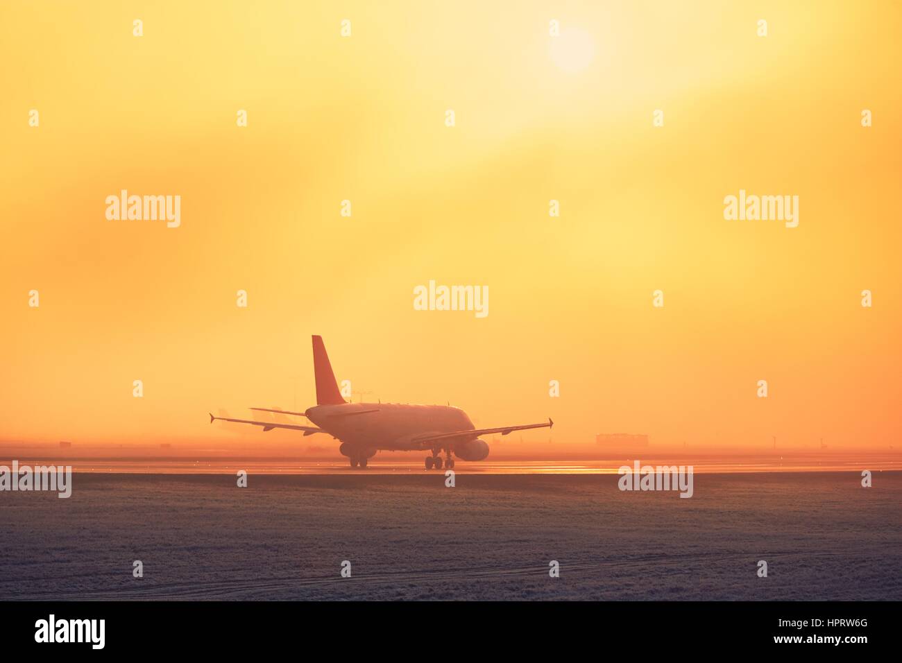 Einfrieren von Nebel am Flughafen. Flugzeug beim goldenen Sonnenuntergang ausziehen. Stockfoto